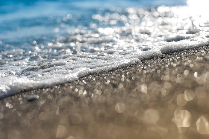 Sand beach and sea foam macro with narrow focus background