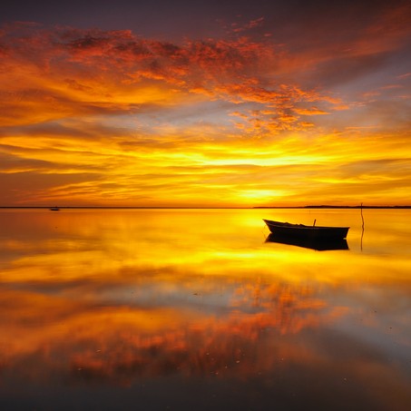 Reflection of Single Boat with Burning Sky During Sunrise
