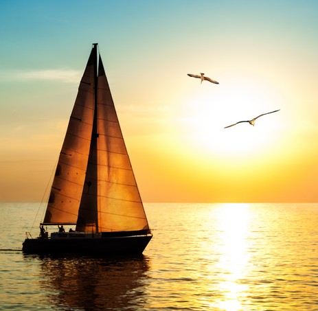 Yacht sailing against sunset